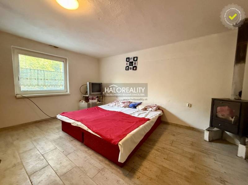 A bedroom with a stove, television, and bed, with a wooden decor floor.