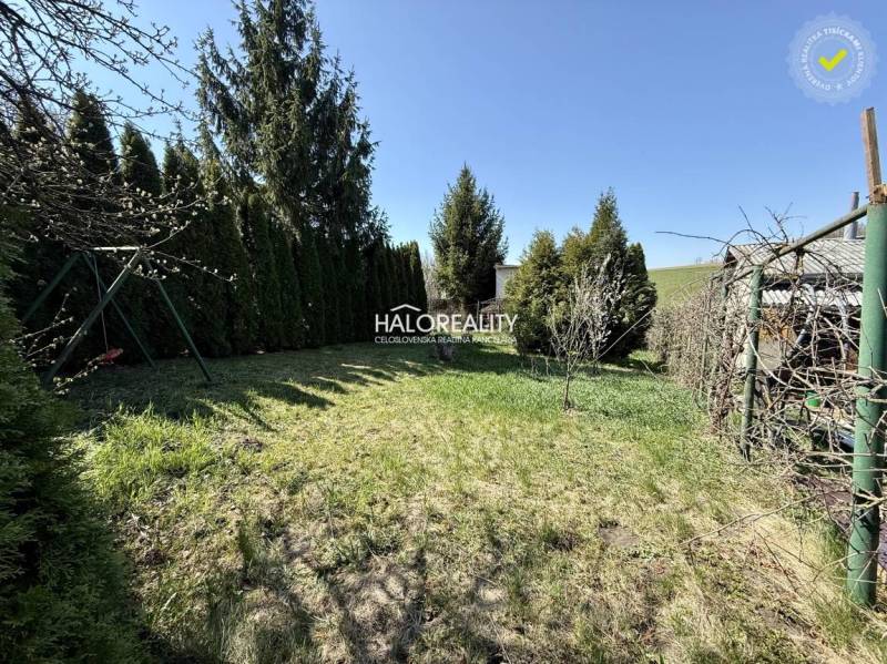 Gardens in Rimavská Sobota are surrounded by conifers and manicured lawns under a blue sky.