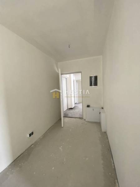 A hallway in a 2-room apartment with white walls, doors, and a floor in a raw state.