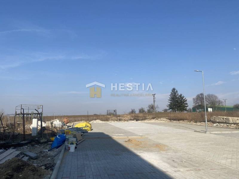 A building and exterior with an empty lot, blue sky, trees in the background.