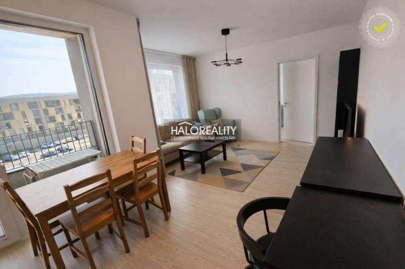 Living room in a 2-room apartment with a balcony, wooden decor flooring, dining table.