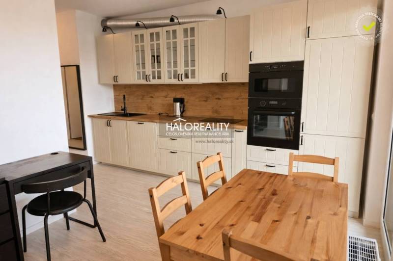 A kitchen in a 2-room apartment with white cabinets and a table with a wood decor.