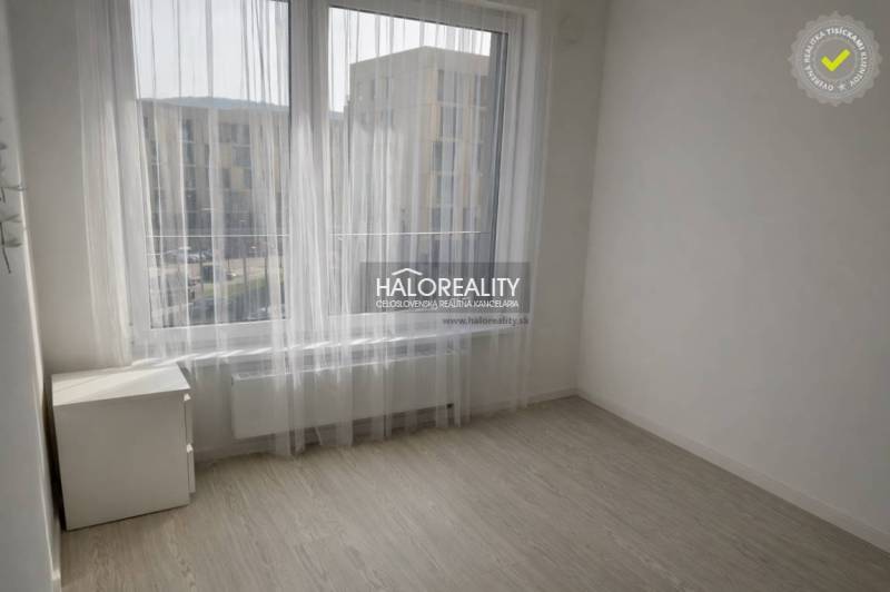 A bright room with large windows and a wooden decor floor in a 2-room apartment.