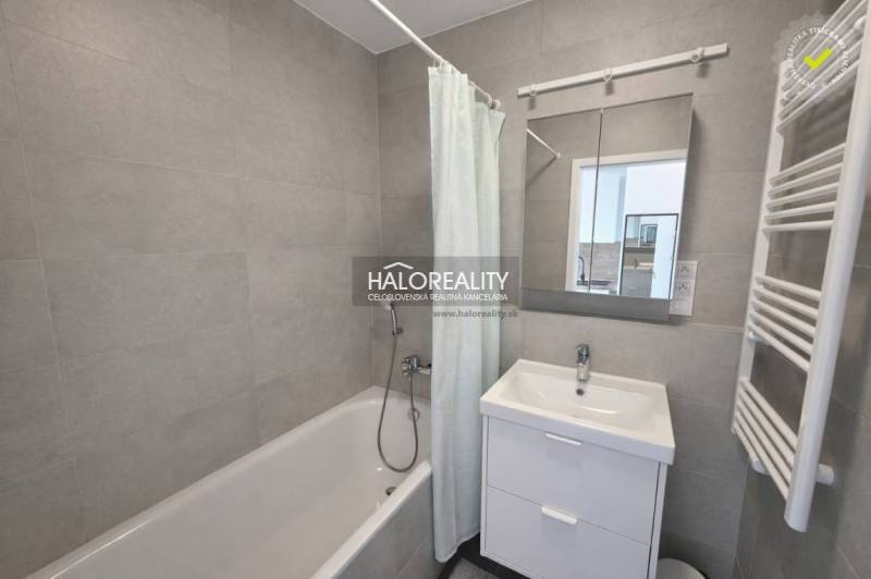 A bathroom with a bathtub, sink, and mirror in a 2-room apartment.
