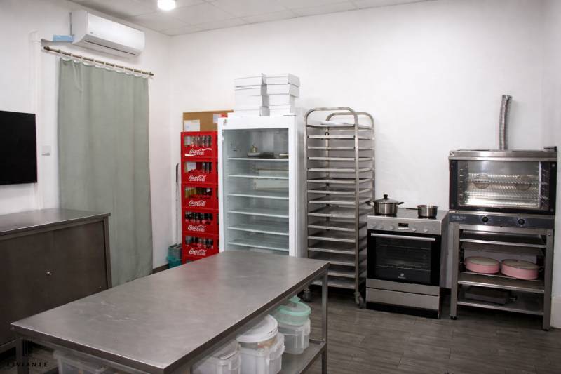 Kitchen gastro spaces with a refrigerator, oven, shelves, and a beverage dispenser.