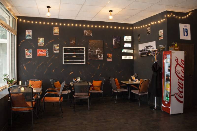 Interior of gastro spaces with car decor, chairs, and flooring with wooden decor.