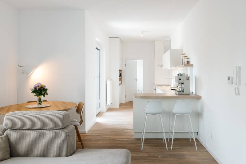 A kitchen with a table, sofa, and wooden decor flooring in a 4-room apartment.