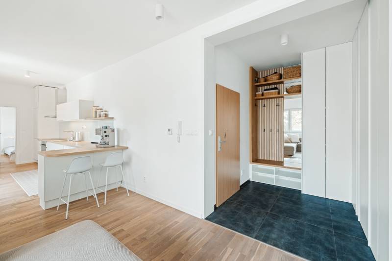 Entrance hallway in a 4-room apartment with a wooden decor floor and a kitchenette.