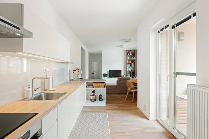 A kitchen with a wooden decor floor and a living room in a 4-room apartment.
