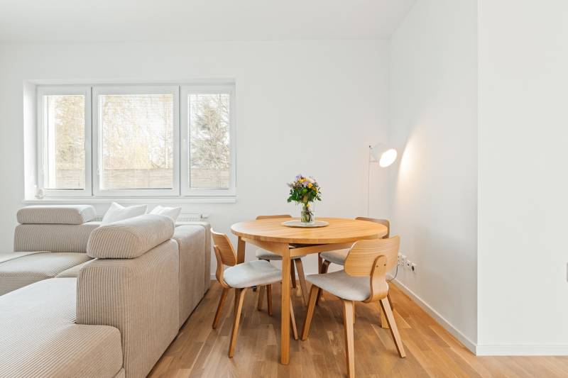 Dining area with a table and chairs in a 4-room apartment with a wooden decor floor.