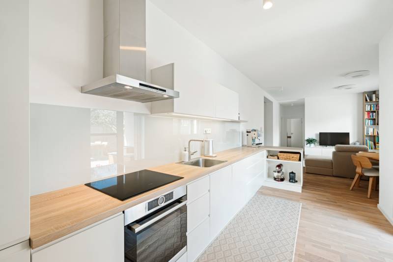 A kitchen in a 4-room apartment with a wood-patterned floor and light furnishings.