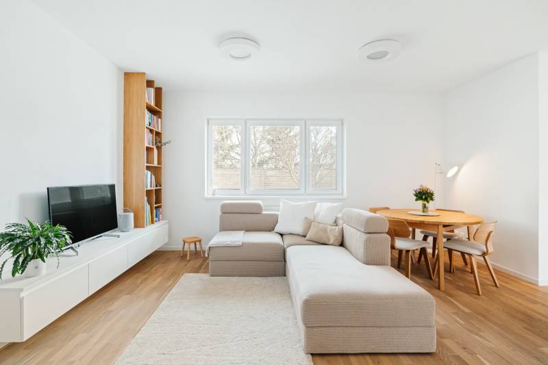 Living room with a sofa, TV, bookshelf, and dining table, floor with wooden decor.