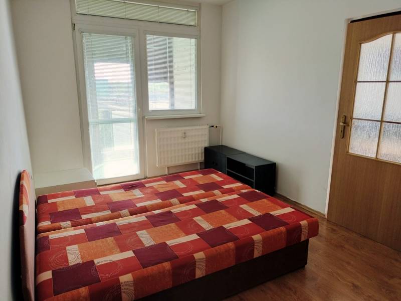 A bedroom in a 3-room apartment with a bed and a wooden decor floor.