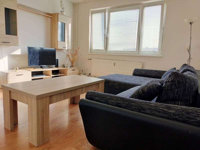 Living room with a sofa, television, and wood-patterned flooring in a 3-room apartment.