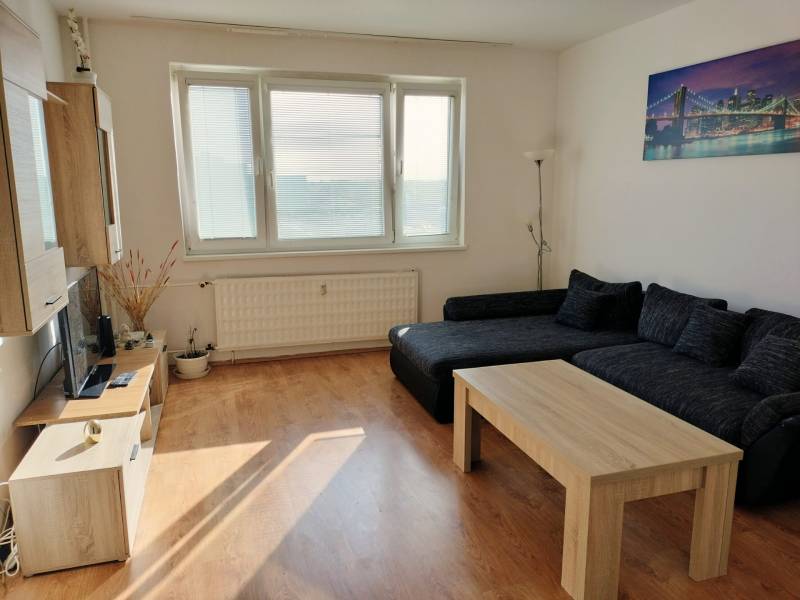 Living room with a sofa, coffee table, and wood-patterned flooring in a 3-room apartment.