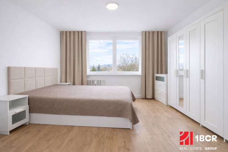 Bedroom with a double bed, wardrobe, and wooden decor flooring in a 2-room apartment.