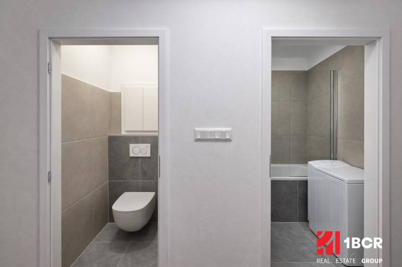Bathroom tiles with a washing machine and toilet in a 2-room apartment.