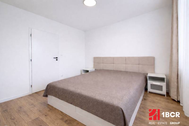 A bedroom in a 2-room apartment with a large bed and a floor with a wooden decor.