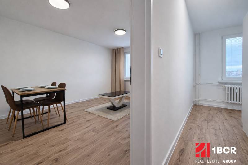 Dining area with a table and chairs in a 2-room apartment with a wooden decor floor.