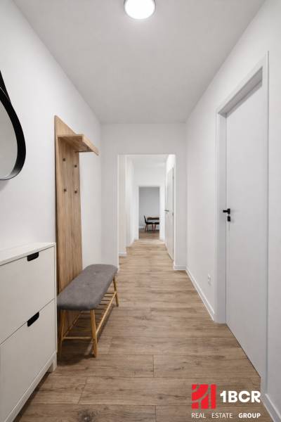 A hallway in a 2-room apartment with a wooden decor floor and a wall-mounted coat rack.