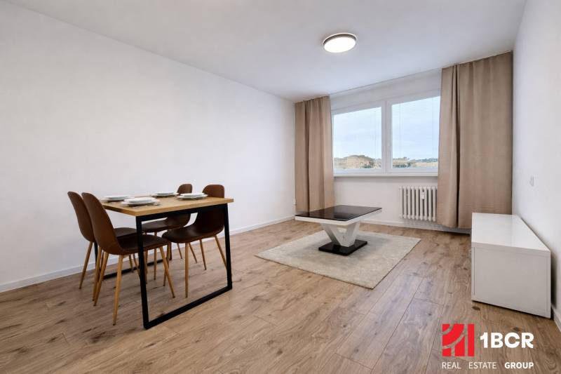 Dining table and coffee table on a floor with a wood decor in a 2-room apartment.