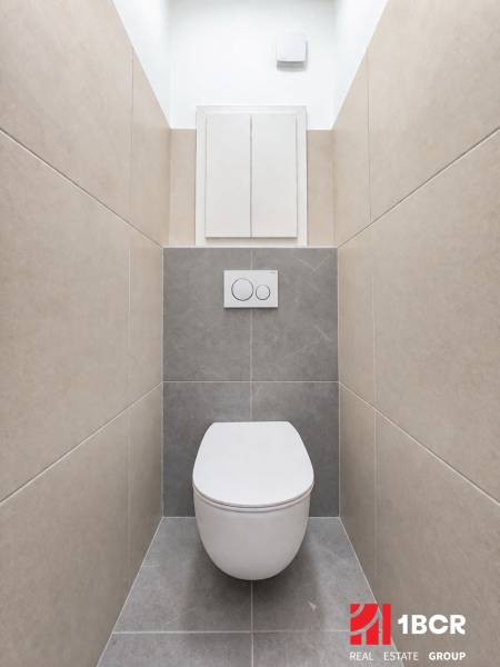 A minimalist bathroom with a wall-mounted toilet and tiles in a two-room apartment.