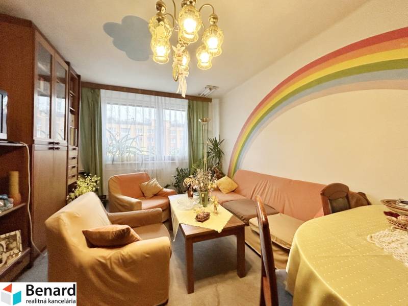Living room in a 3-room apartment with a rainbow on the wall, comfortable sofas, and a table.