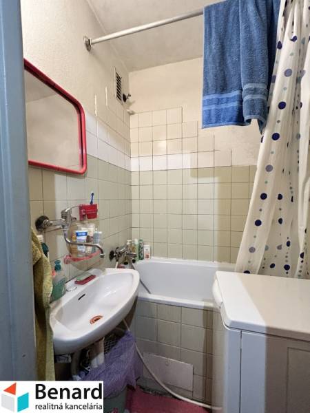A bathroom in a 3-room apartment with a bathtub, sink, and washing machine.