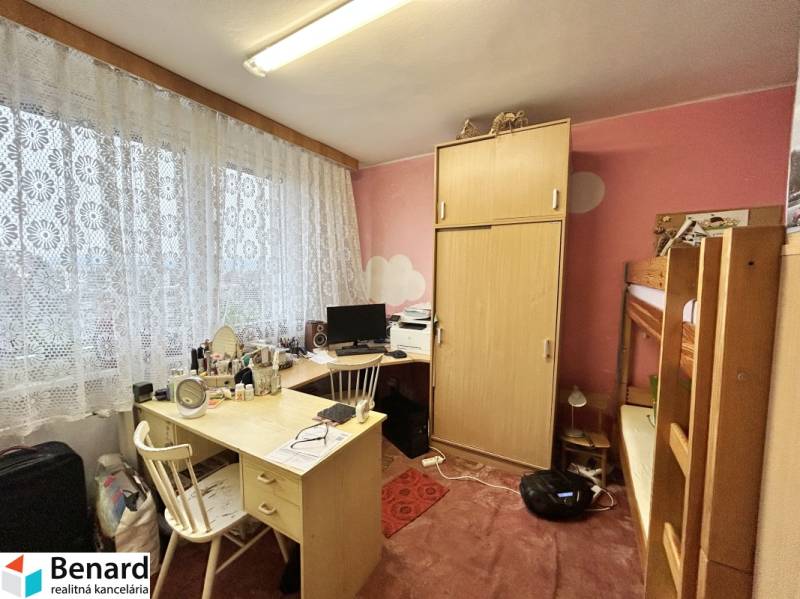 A room with a bunk bed and a desk in a three-room apartment.