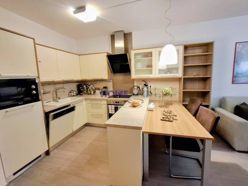 A kitchen in a 2-room apartment with a dining table and a floor with a wood decor.