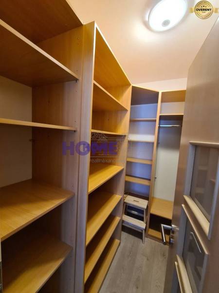 Storage space with shelves in a two-room apartment with a wood-patterned floor.