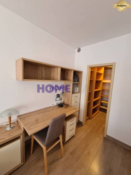 A desk with storage space in a 2-room apartment with a wooden decor floor.