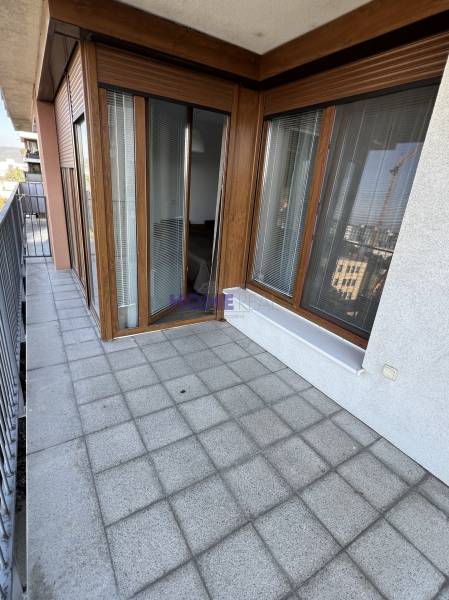 Balcony with tiles and wooden decor, part of a 2-room apartment, with railing and view.