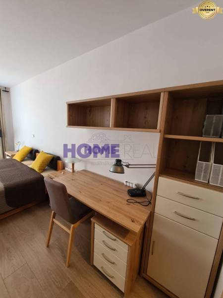 A desk with shelves, a bed, and a floor with a wooden decor in a 2-room apartment.