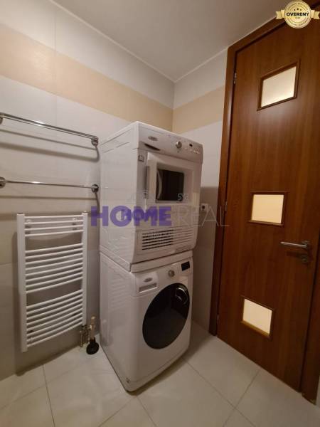 Bathroom in a 2-room apartment with a washing machine and dryer, white radiator on the wall.