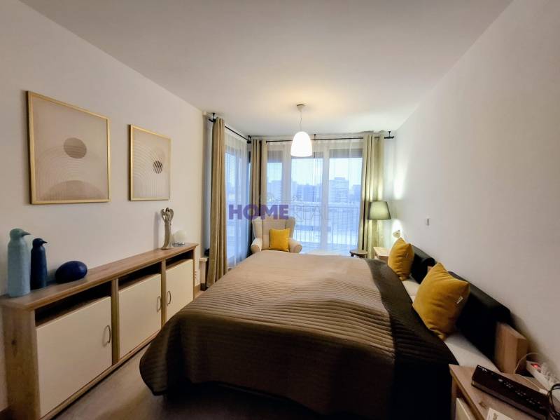 Bedroom with a bed, decorative pillows, and a dresser in a two-room apartment.