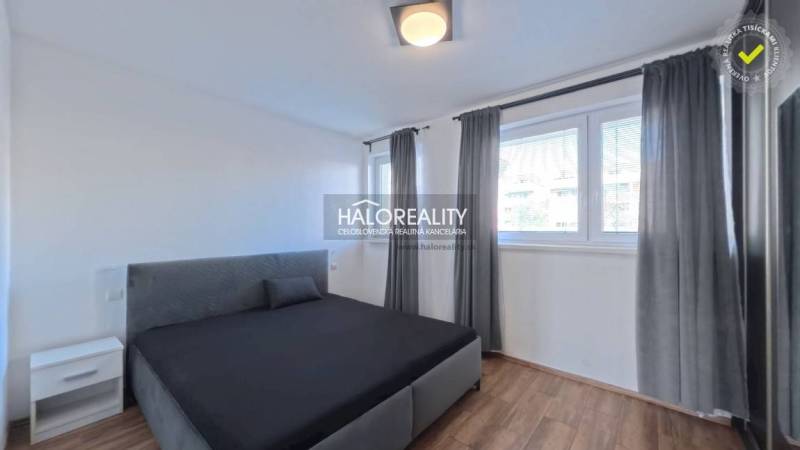 Bedroom with a bed in a 2-room apartment, windows with blinds, floor with wooden decor.