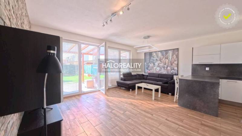 2-room apartment with wood-patterned flooring, a sofa, and a kitchenette.