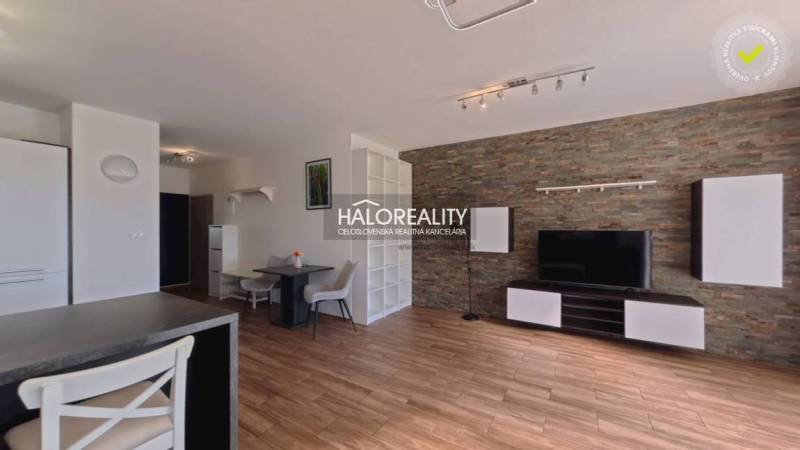 Living room in a two-room apartment with a wooden decor floor and stone cladding.