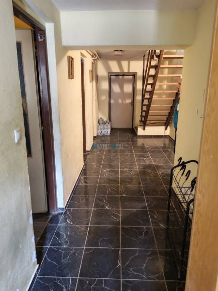 Interior of a family house with dark tiles and a wooden staircase.