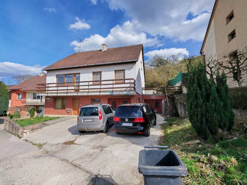 A family house on Závršky Street in Myjava, a parking lot with two cars and greenery.