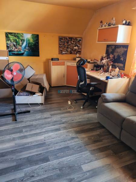A room in a family house with a desk, a chair, and a floor with a wooden decor.