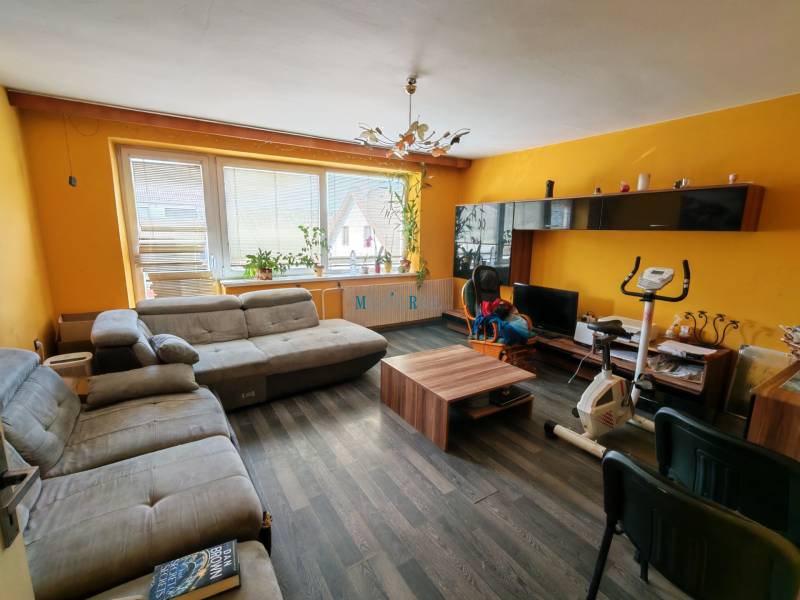 Living room of a family house with a wooden decor floor and yellow walls.