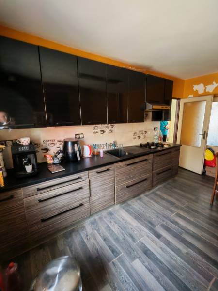 A kitchen with black cabinets and a wood-decorated floor in a family house.