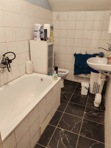 A bathroom in a family house with a bathtub, a sink, and tiles with a dark pattern.