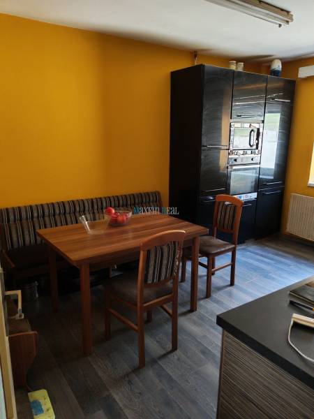 Dining room in a family house with a wooden table, chairs, and a floor with a wooden decor.