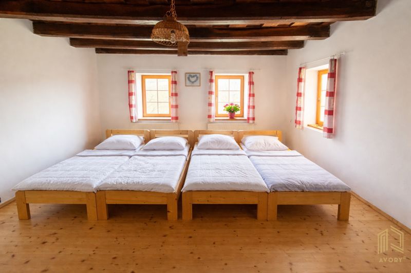 Wooden beds and ceiling beams in a family house with a floor featuring a wood decor.