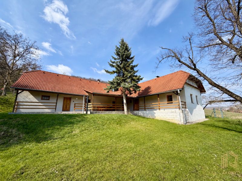 A family house in Podbranč with a red roof surrounded by greenery and trees.