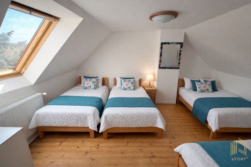 Attic bedroom with four beds and a wooden decor floor in a family house.