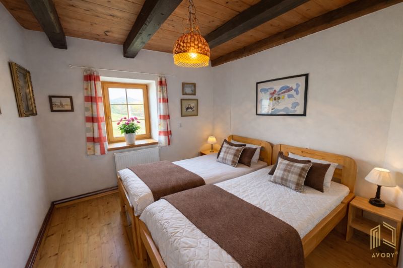 A bedroom in a family house with two beds and a floor with a wooden decor.